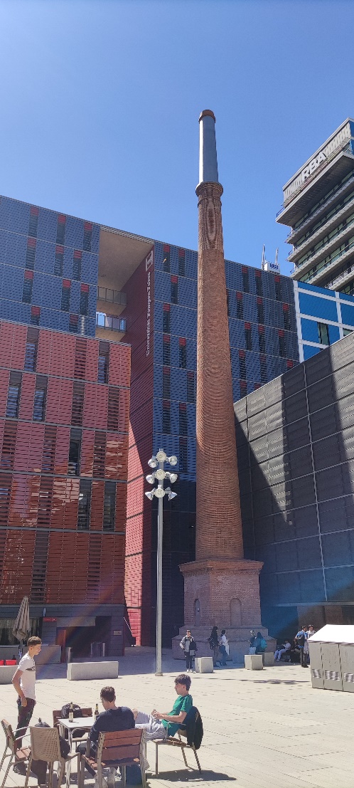 A tall stone pillar in front of a building
Description automatically generated